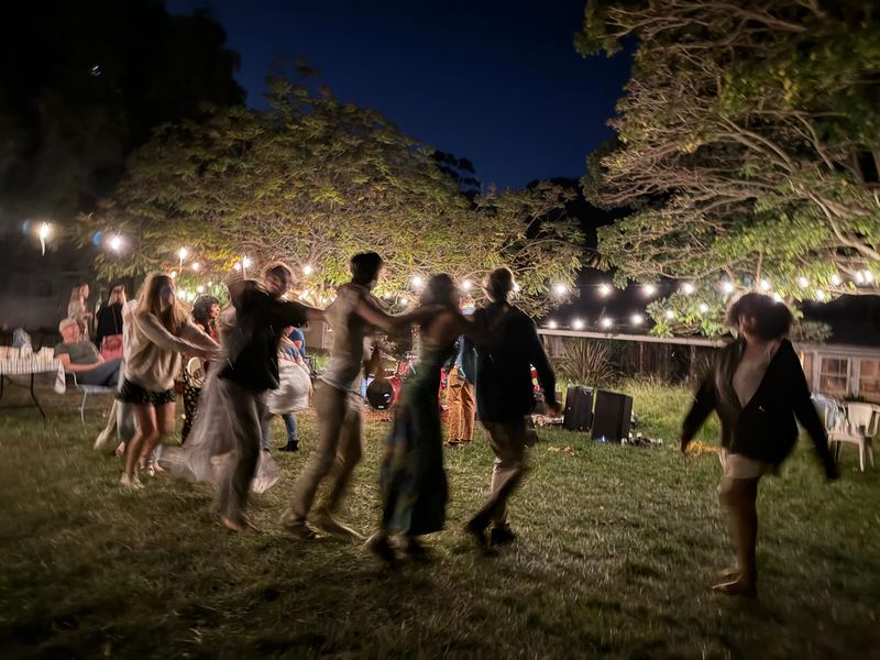 Guests dancing under string lights at night.