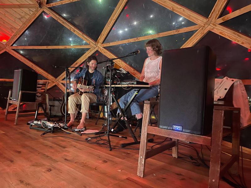A husband-and-wife band playing in a wooden dome.