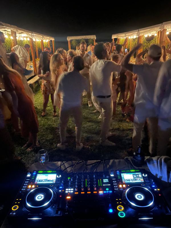 A crowd dancing beside the DJ decks.